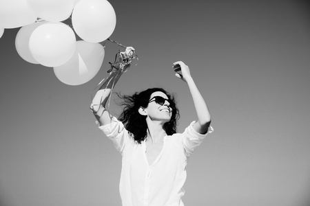 woman holding white balloons on seasideの写真素材