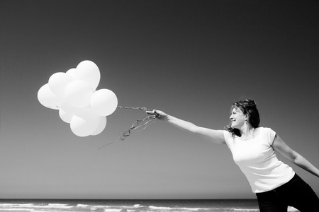 Beautiful redhead woman holding white balloonsの写真素材