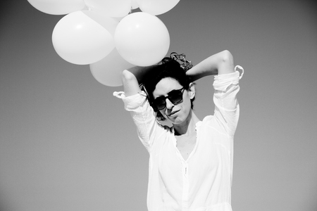 woman holding white balloons on seasideの写真素材