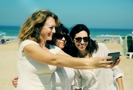three best friends walking on the seasideの写真素材