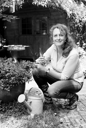 Portrait of beautiful 40 years old woman gardening on sunny day in the gardenの写真素材