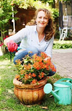 Portrait of beautiful 40 years old woman gardening on sunny day in the gardenの写真素材