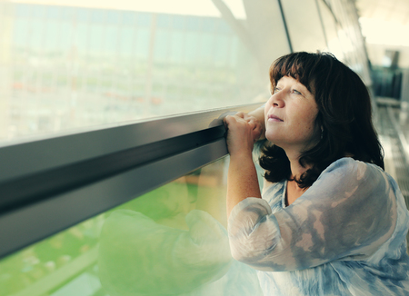 Portrait of beautiful 40 years old woman standing near the windowの写真素材