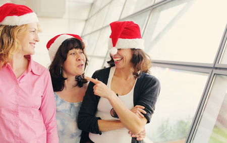 Portrait of three beautiful real women wearing christmas hatの写真素材