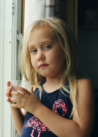 5 years old girl holding glass of milkの写真素材