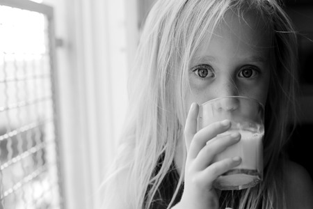 5 years old girl holding glass of milkの写真素材