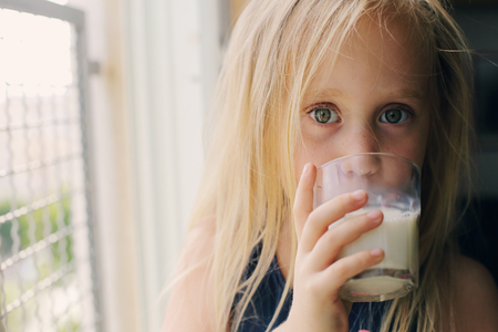 5 years old girl holding glass of milkの写真素材