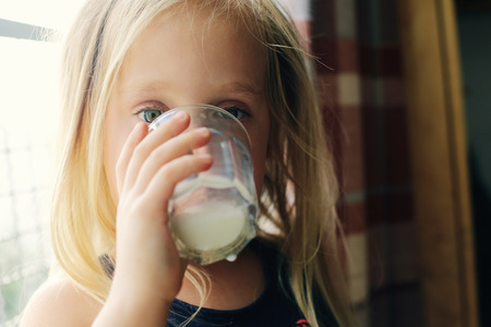 5 years old girl holding glass of milkの写真素材