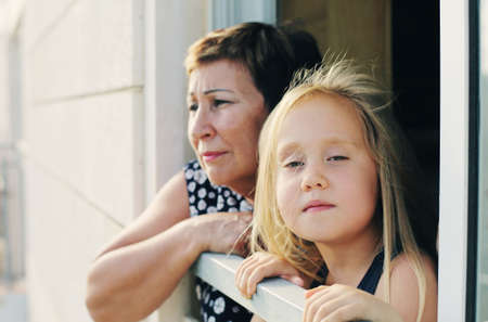 grandmother with her grandchild looking from the windowの写真素材