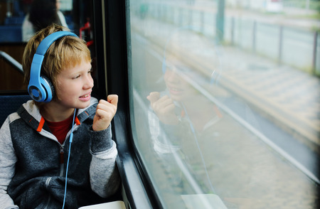 Cute 8 years old boy looking through the window in the trainの写真素材