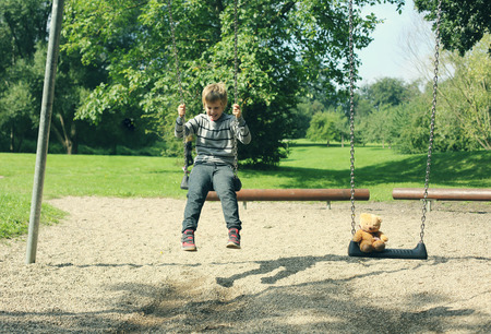 Cute autistic child sitting on the swing in the parkの写真素材