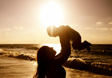 Portrait of happy loving mother and her baby at the beachの写真素材