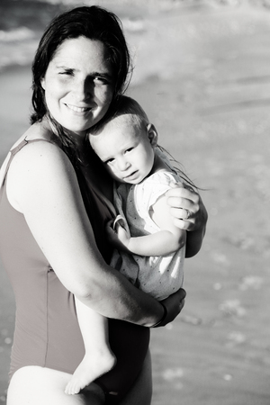 Portrait of happy loving mother and her baby at the beachの写真素材