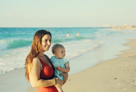 Portrait of happy loving mother and her baby at the beachの写真素材