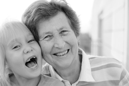Portrait of beautiful 70 years old woman with 5 years old granddaughterの写真素材