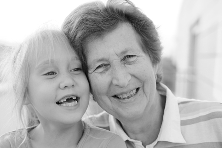 Portrait of beautiful 70 years old woman with 5 years old granddaughterの写真素材