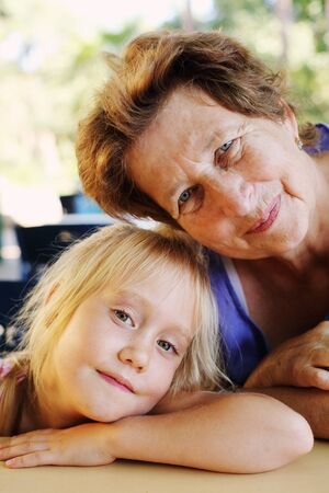 Portrait of beautiful 70 years old woman with 5 years old granddaughterの写真素材