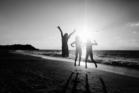Three girlfriends jumping on the beach at sunsetの写真素材