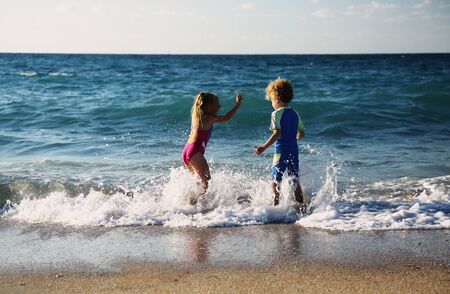 kids playing on the beach at sunsetの写真素材