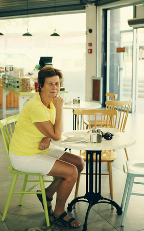 Portrait of beautiful 70 years old woman sitting in cafeの写真素材