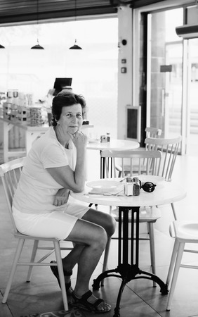 Portrait of beautiful 70 years old woman sitting in cafeの写真素材