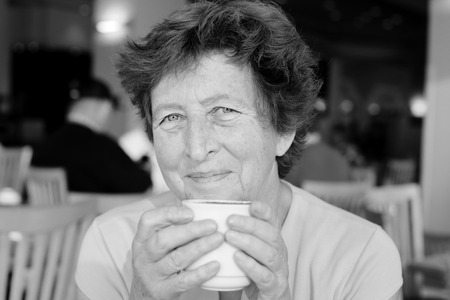 Portrait of beautiful 70 years old woman drinking morning coffeeの写真素材