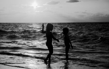 kids playing on the beach at sunsetの写真素材