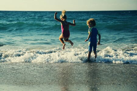 kids playing on the beach at sunsetの写真素材