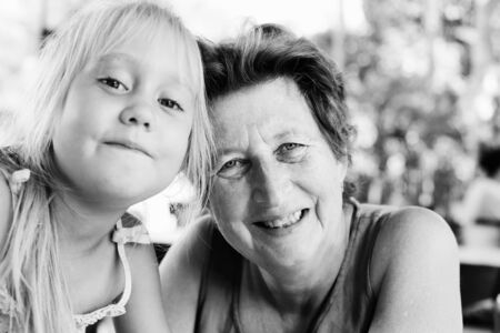Portrait of beautiful 70 years old woman with 5 years old granddaughterの写真素材