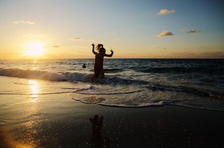 kids playing on the beach at sunsetの写真素材