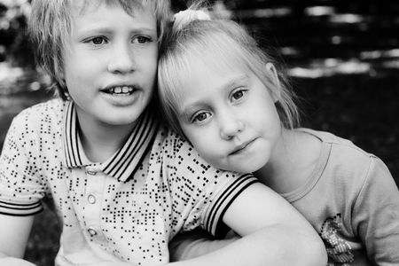 Portrait of happy 5 years old girl with her autistic 8 years old brother outdoorsの写真素材