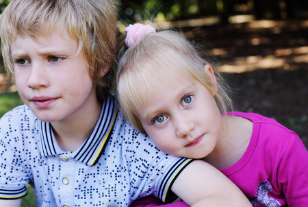 Portrait of happy 5 years old girl with her autistic 8 years old brother outdoorsの写真素材