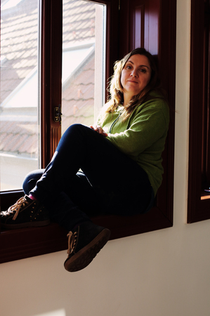 Portrait of beautiful sad woman looking throught the windowの写真素材
