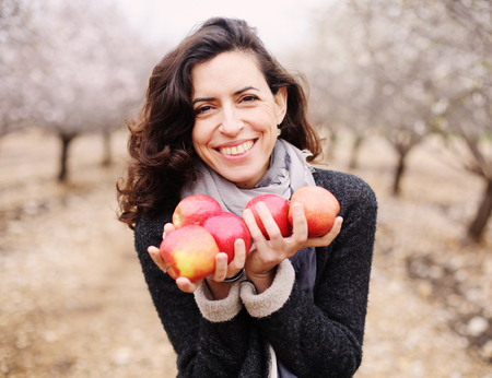 Outdoor portrait of 40 years old woman holding red applesの写真素材