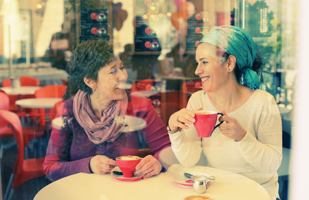 Two happy 45 years old woman sitting in the city cafeの写真素材