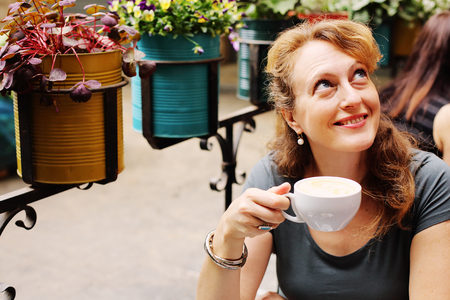 Portrait of beautiful 40 years old woman sitting in outdoor cafeの写真素材