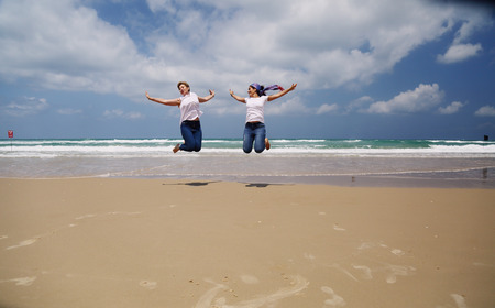 Outdoor portrait of two women jumping on the beachの写真素材