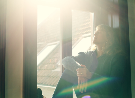 Portrait of beautiful real woman looking throught the windowの写真素材