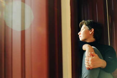 Portrait of beautiful real woman looking throught the windowの写真素材