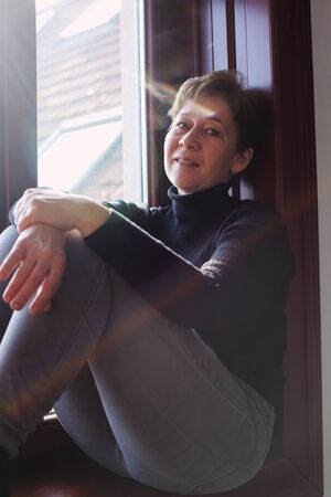 Portrait of beautiful real woman looking throught the windowの写真素材