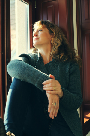 Portrait of beautiful real woman looking throught the windowの写真素材