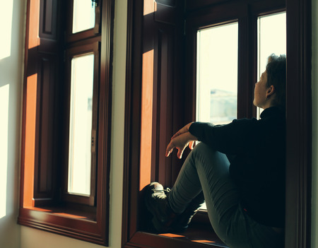 Portrait of beautiful real woman looking throught the windowの写真素材