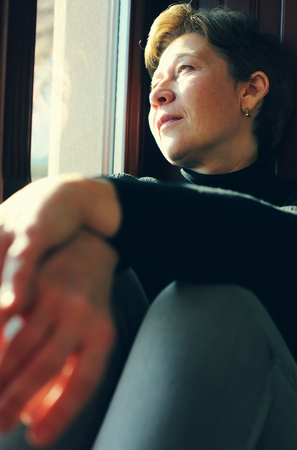 Portrait of beautiful real woman looking throught the windowの写真素材
