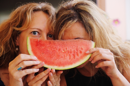 Portrait of two 40 years old woman eating watermelonの写真素材