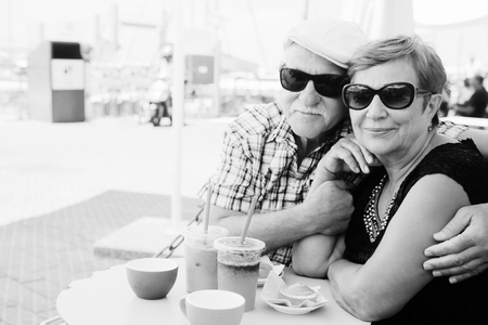 Portrait of senior couple sitting in summer cafeの写真素材