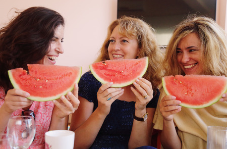 Portrait of three 40 years old woman eating watermelonの写真素材