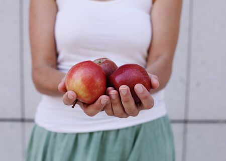 Beautiful woman is holding with freshly organic red applesの写真素材
