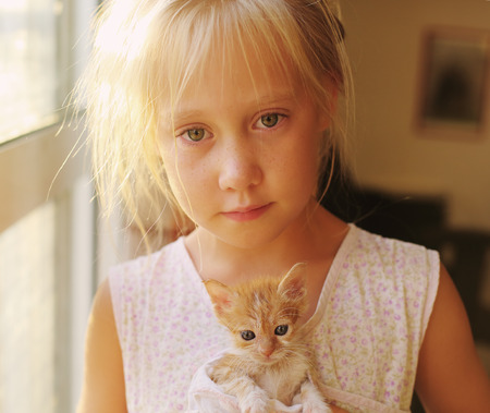 Portrait of 6 years old girl with cute red kittenの写真素材