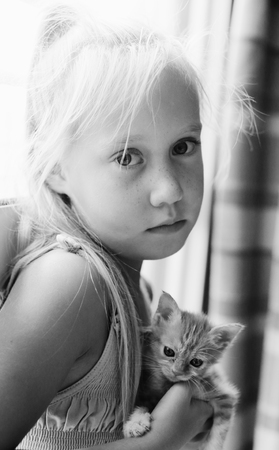 Portrait of 6 years old girl with cute red kittenの写真素材