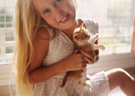 Portrait of 6 years old girl with cute red kittenの写真素材